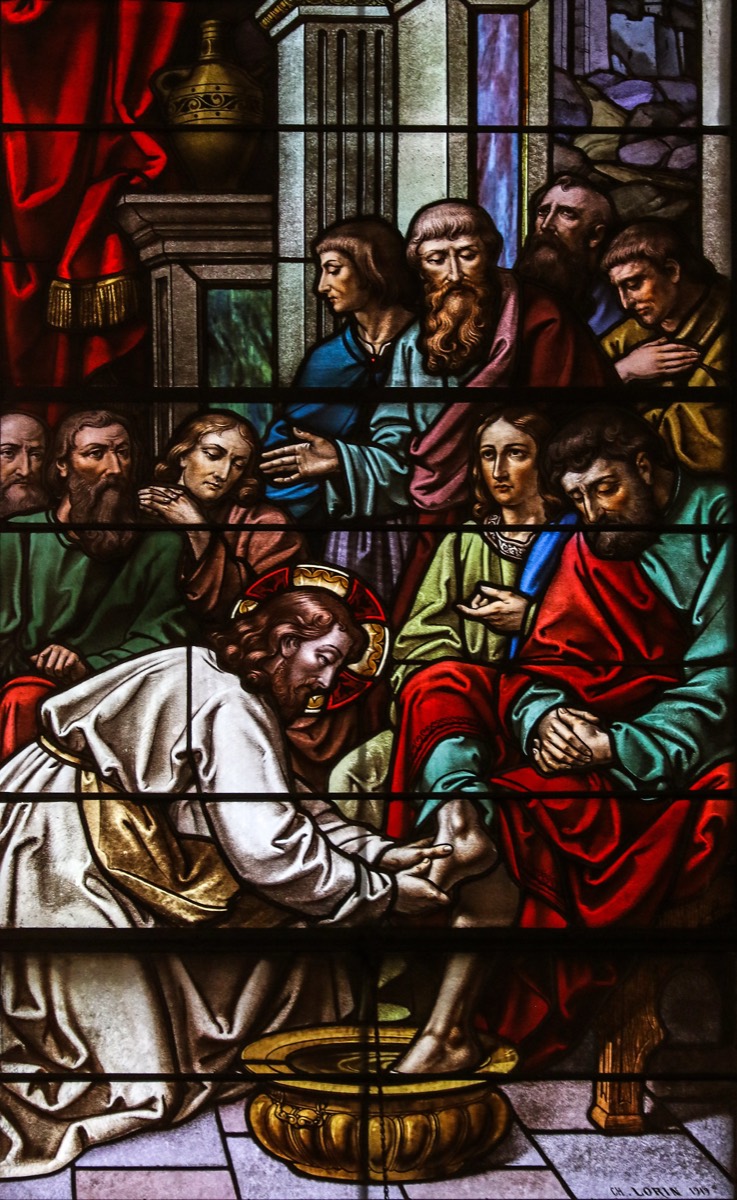 A stained-glass window of Christ washing the feet of his disciples.